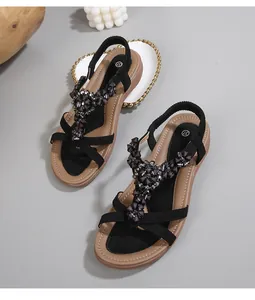 Détail de sandales bohèmes plates à bride en T avec strass sombres et bride arrière élastique
