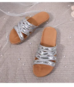 Detail of silver sequin cross strap sandals on brown footbed with elegant pearls