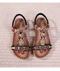 Dettaglio di sandali piatti boho con perline colorate, ciondoli e motivi floreali etnici