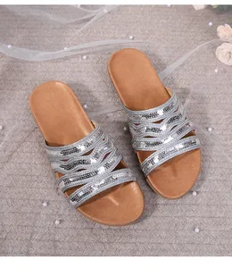 Detail showing silver sequin straps and brown leather cushioned footbed on flat sandals