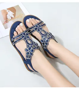 Dettaglio di sandali blu scuro con strass floreali e cinturino elastico al tallone