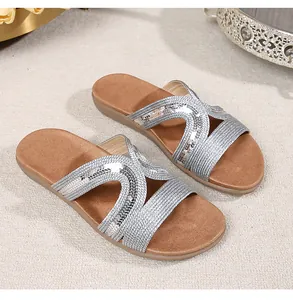 Macro view of silver rhinestone flat sandals on a decorative tray for bohemian summer wear