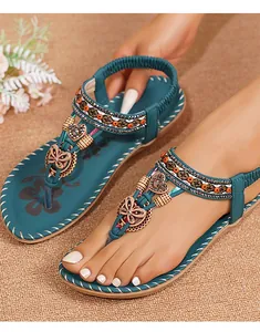 Detail van bohemian platte sandalen met T-strap, kralen, vlinders en een bloemenvoetbed