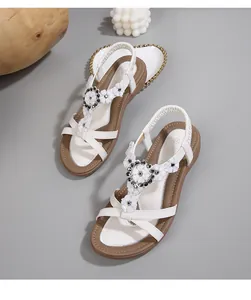 Détail de sandales bohèmes blanches avec fleurs et lanières en T ornées de perles