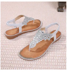 Close-up of sparkling rhinestones and golden metal trim on bohemian flat sandals
