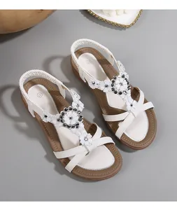 Détail de sandales blanches bohèmes à bride en T avec fleurs 3D et strass étincelants