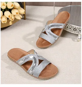 Detailed view of women's flat sandals featuring silver sequin cross straps and a brown sole