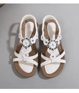 Détail de sandale compensée blanche bohème avec fleurs 3D et ornements de perles grises