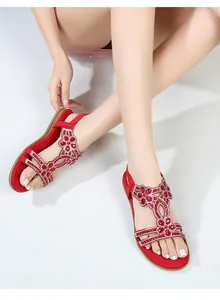 Dettaglio di sandali boho rossi con raffinati strass rossi e argento decorativi