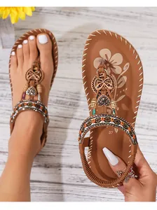 Detail van boheemse platte sandalen met kristallen enkelbandje en metalen vlinderkralen