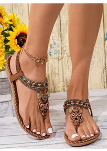 Detail van boho platte sandalen met kleurrijke kralen en vlinderbedels aan de voet