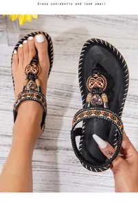 Detail van zwarte bohemian slippers met metalen strik, kralen en geborduurde band