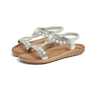 Détail de sandales bohèmes argentées avec perles blanches, strass et bride élastique