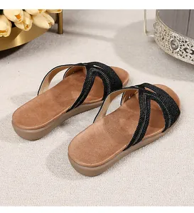 Detail shot of black woven criss-cross straps on bohemian flat sandals with cushioned footbed