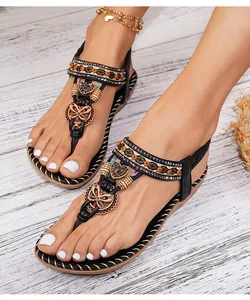 Detail van bohemien platte sandalen met kleurrijke kralen, strassteentjes en vlinderbedels