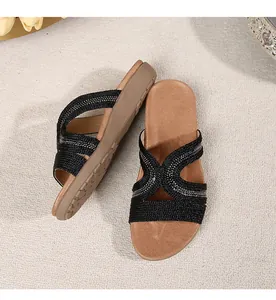 Detailed top view of black woven flat sandals with rhinestone accents and thick rubber soles