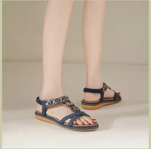 Detailansicht von blauen Bohème-Sandalen mit bunten Perlen und Pailletten am Fuß