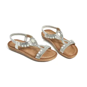 Détail de sandales bohèmes argentées avec strass brillants et perles blanches sur bride T