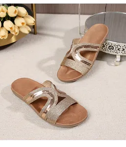 Close-up of golden sequins on cross-strap flat sandals with soft suede footbed