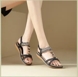 Detail of bohemian flat sandals featuring heart-shaped metal buckles and elastic straps