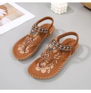 Detail van bohemien platte sandalen met bruine kralenbandjes en metalen vlinderbedeltjes
