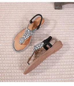 Detailed view of bohemian t-strap flat sandals featuring dense white rhinestone patterns