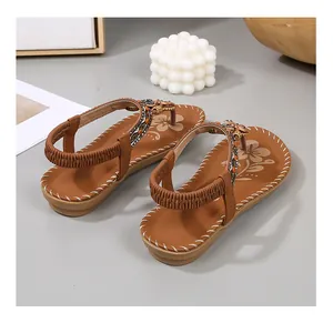 Detail van bohemian platte sandalen met T-strap, kralen, metalen bedels en elastiek