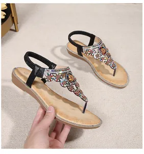 Close-up of bohemian wedge sandals featuring colorful rhinestone flowers and T-strap design