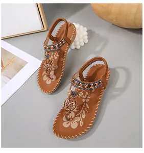 Detail van bohemian platte sandalen met kleurrijke kralen en metalen vlinderbedels