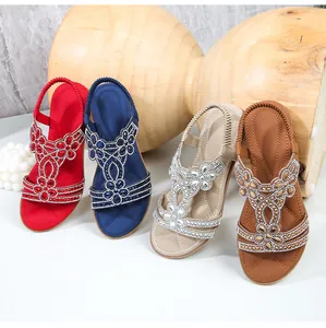 Dettaglio di sandali piatti bohémien con strass in rosso, blu, beige e marrone