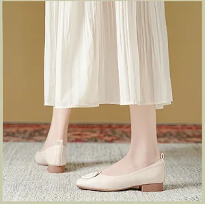 Detail van gebroken witte leren ballerina's met een vierkante gesp en zachte platte zool