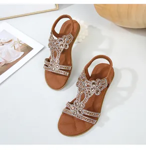 Dettaglio di sandali piatti bohemian con motivi floreali in strass e cinturino elastico
