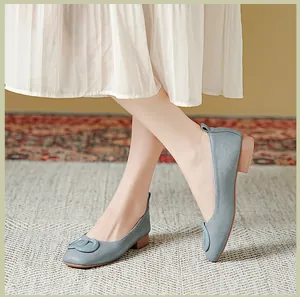 Detail van lichtblauwe leren loafers met ring en een witte geplooide rok erbij