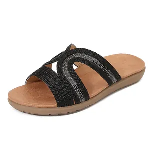 Women's bohemian flat sandals with black woven straps and sparkling rhinestone accents