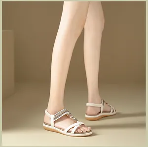 Detail of white flat sandals featuring pearls, rhinestones, and gold chain straps