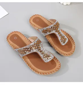 Detalle de sandalias planas bohemias con brillantes pedrería y suela de cuero marrón