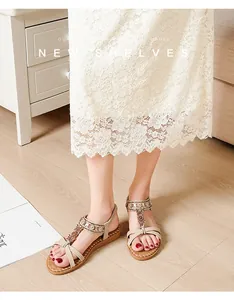 Detailed view of rhinestone flower beads and T-strap on beige flat beach sandals
