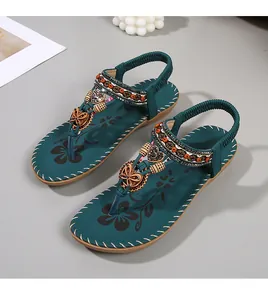 Detail van bohemien groenblauwe platte sandalen met hartvormige kralen en bloemenprint zool