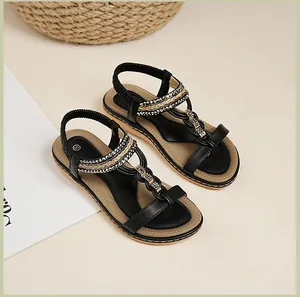 Detail von schwarzen flachen T-Steg-Sandalen mit Metallperlen und elastischem Fersenriemen