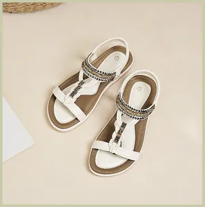 Draufsicht auf flache Boho-Sandalen mit Kettendetails und weißem elastischem Fersenriemen