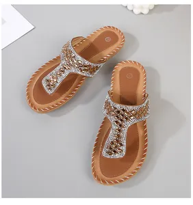 Detalle de sandalias planas bohemias con pedrería brillante y costura a la vista