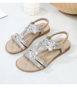 Dettaglio di sandali estivi beige con fiori di strass intrecciati e cinturino elastico sul retro