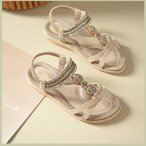Detail of beige bohemian flat sandals with sparkling gold heart-shaped metal buckles