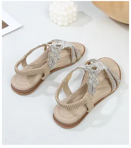 Dettaglio di sandali bassi beige con motivi floreali in strass e cinturino elastico sul tallone