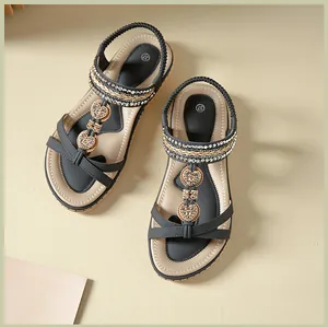 Detail view of T-strap flat sandals featuring heart rhinestone buckles and elastic back strap