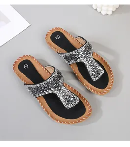 Detalle de sandalias bohemias planas con pedrería plateada y suelas cosidas a mano