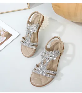 Dettaglio dei sandali beige con cinturino a T con fiori di strass e cinturino elastico