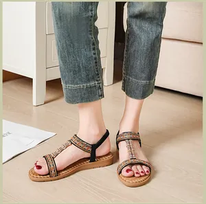 Detalle de sandalias planas bohemias con bordado étnico y tiras de cuentas en una modelo
