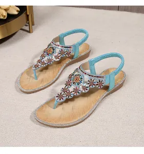 Detail of bohemian flat sandals with sparkling rhinestone flowers and blue T-strap design