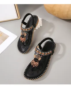 Detailweergave van zwarte boho sandalen met etnische kralen en metalen bedeltjes